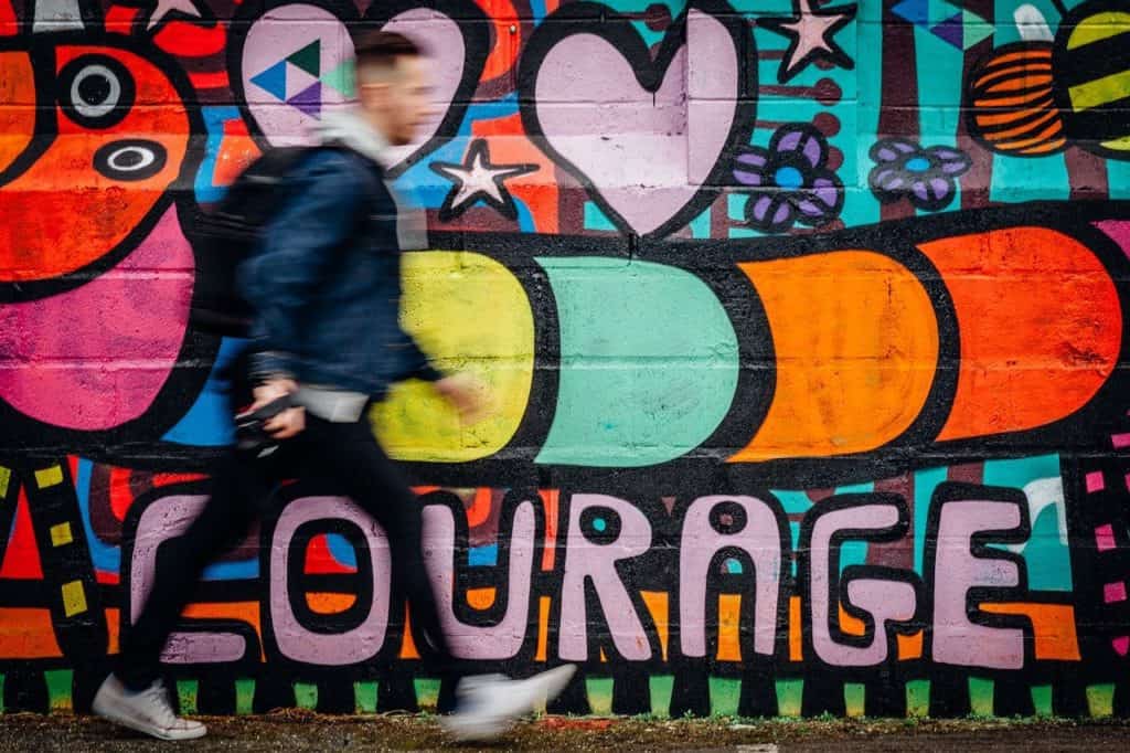 Image of wall of graffiti that says "courage."