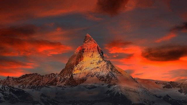 Image of the Matterhorn (mountain) bathed in coral light from a sunset or sunrise.