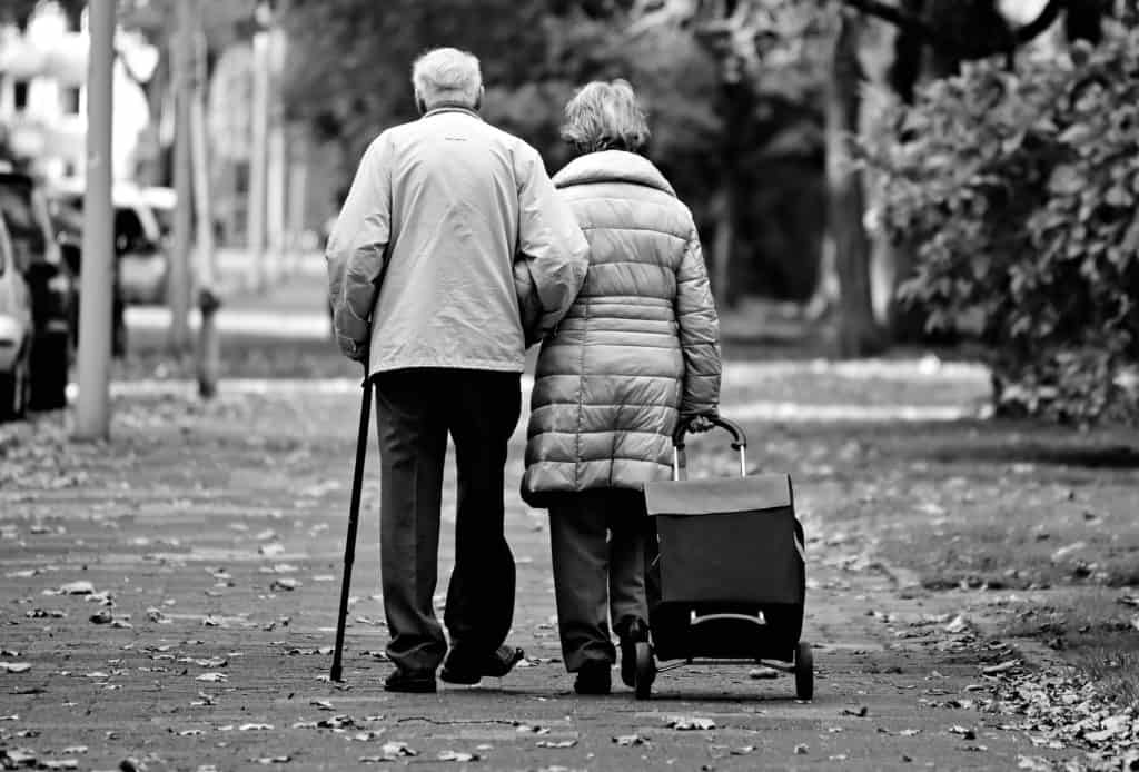 Image of two elderly people walking arm in arm away from the camera. Marriage is for life!