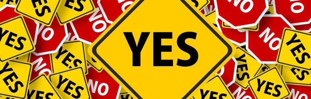 Image of overlapping road signs. Stop signs have the word "No" printed on them and yellow signs have the word "Yes" printed on them.