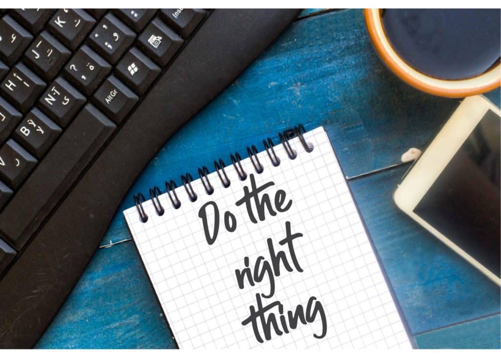 Image of a notepad on which it is written "do the right thing" next to a computer keyboard, a cell phone, and a cup of coffee on a teal wood table.