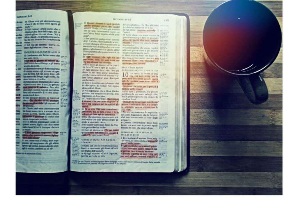 Image of open Bible with many highlighted passages next to a mug of coffee.