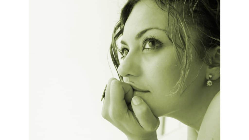 Close-up image of a woman lost in thought with her head on her hand. She is waiting on God, thinking about being grateful and what the future might hold.