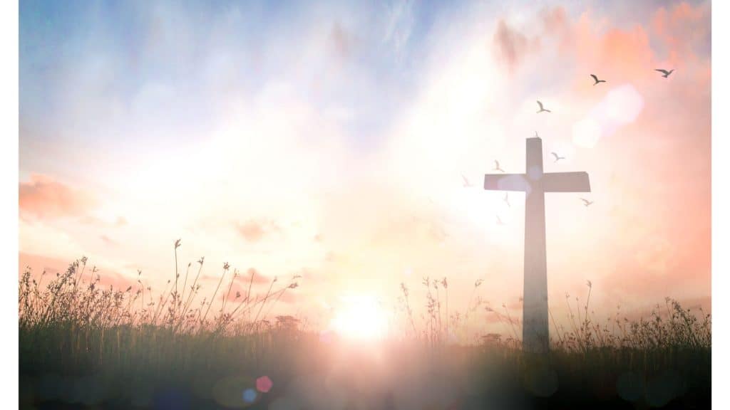 Image of a cross and birds in silhouette with the sun rising in the background.