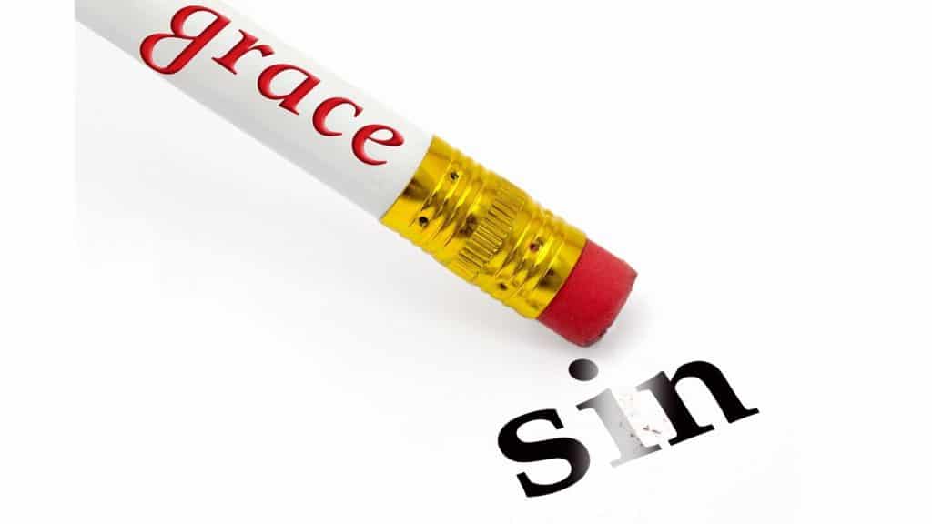 Pencil with word "grace" on it erasing the word "sin," which is printed on a piece of paper.