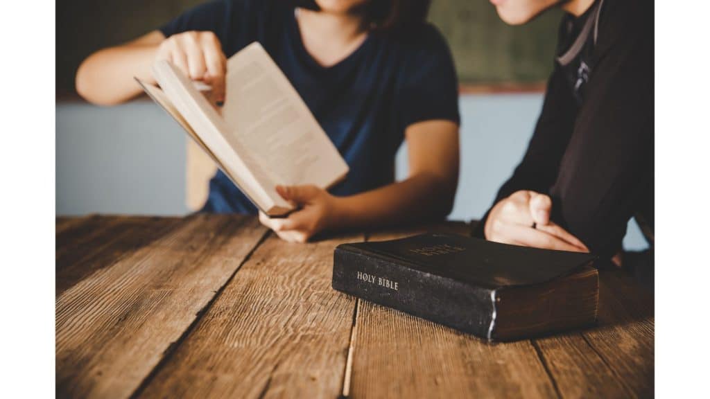 Woman pointing out Bible verses about being a conqueror to someone.