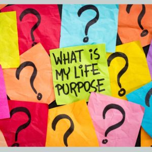 "What is my life purpose?" written on a sticky note surrounded by sticky notes with question marks on them.