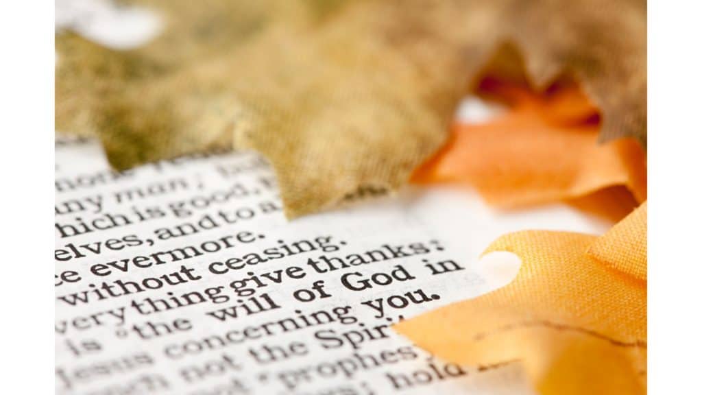 Bible verse open to page about giving thanks surrounded by autumn leaves.