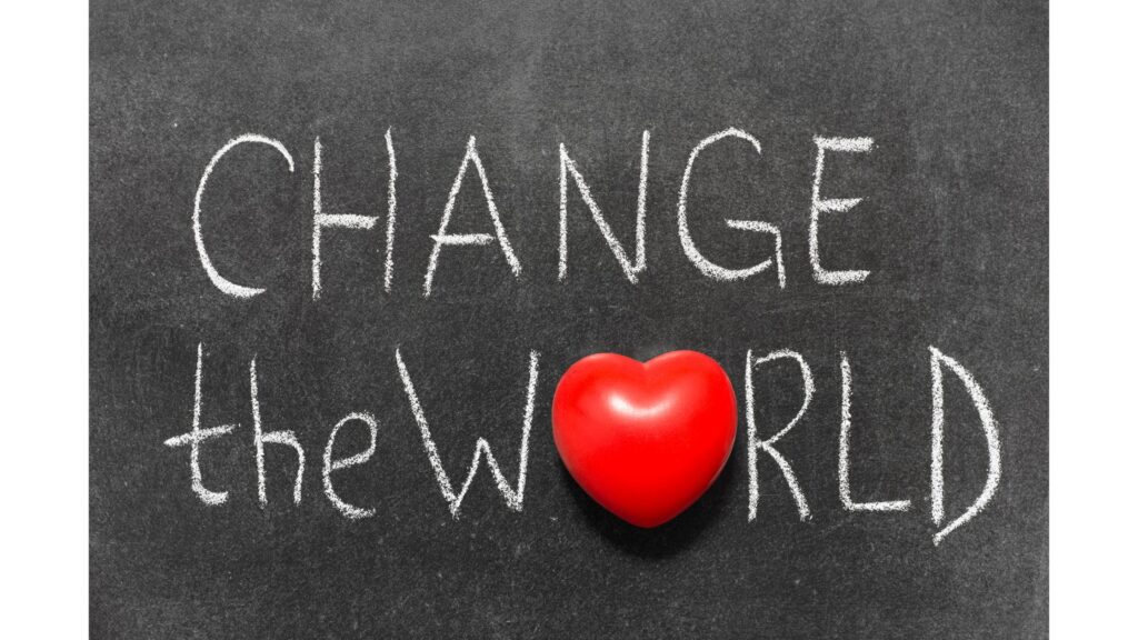 "Change the world" written in chalk on a chalkboard. The "O" in "world" has been replaced by a red heart.