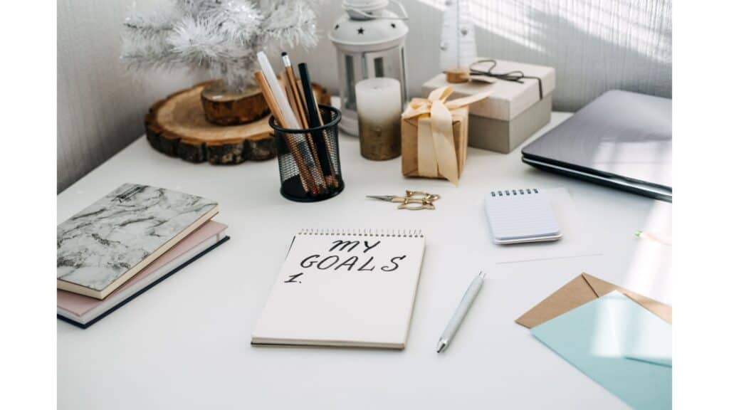 The words "My goals" written on a notepad, which is sitting on a desk surrounded by pretty desk accessories.