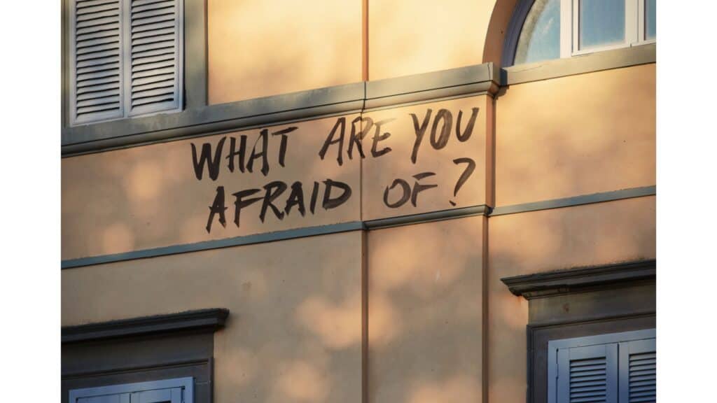 The words "What are you afraid of?" painted on the side of a building.