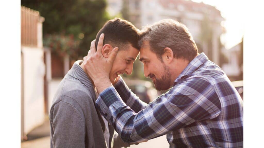 Man and son standing forehead to forehead looking happy to see each other.