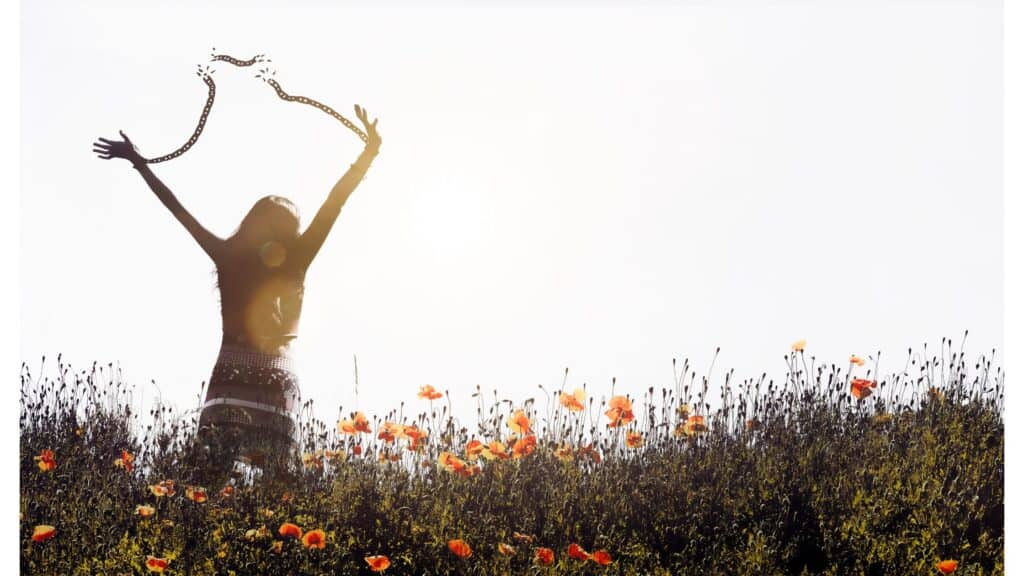 Illustration of freedom from sin - woman standing in a field of flowers throwing her hands up in the air and breaking the chains that bind her wrists.