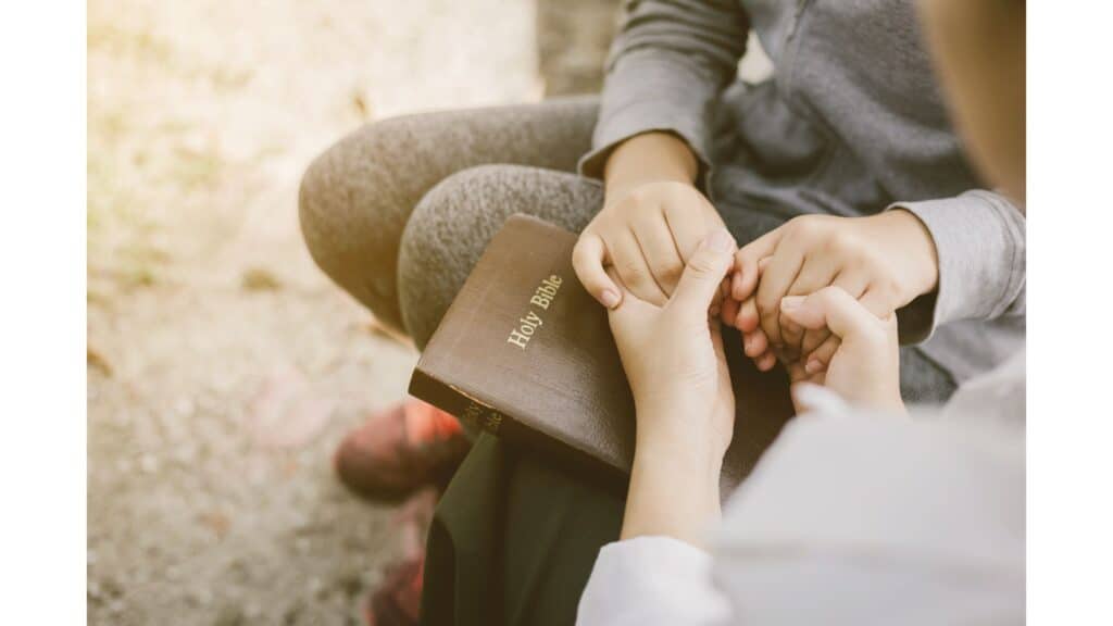 Two womens' hands holding on top of a Bible.